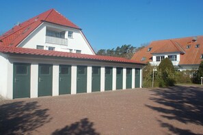 A building with a red-tiled roof, multiple green doors, and a brick pathway. - Holiday apartment with 1 bedroom (Ostseebad Prerow)