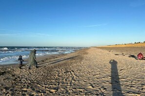 A beach with a clear sky, a sandy shore, and a few people walking. - Holiday home with 2 bedrooms (Ribnitz-Damgarten)