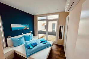 A bedroom with a bed, a nightstand, a window, and a painting on the wall. - Holiday home with 2 bedrooms (Ribnitz-Damgarten)
