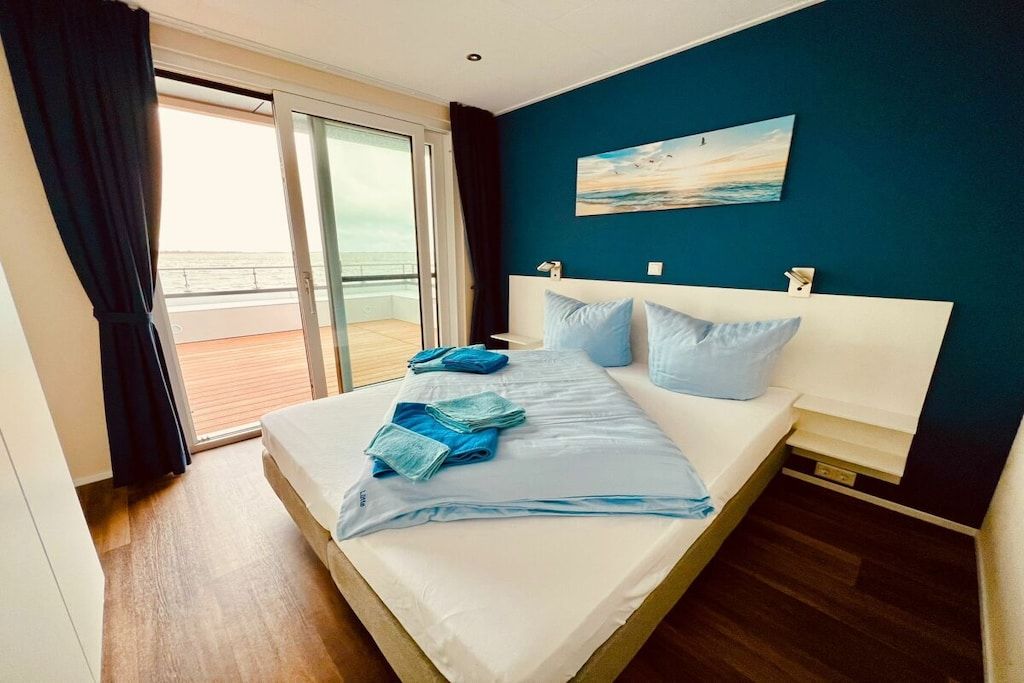 Une chambre d’hôtel avec un lit, un tableau au mur et une vue sur l’extérieur, visible à travers une porte coulissante.