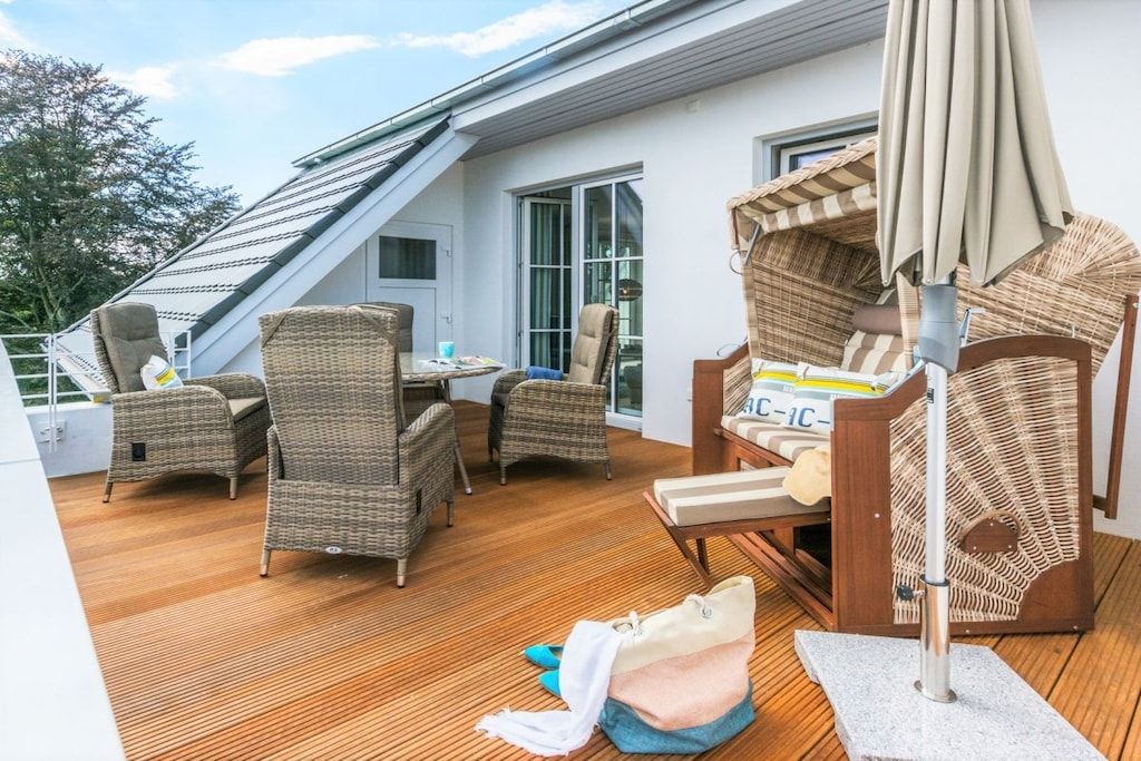 Un espace extérieur abrité, aménagé avec des meubles en osier, une table et une chaise dotée d’un auvent.