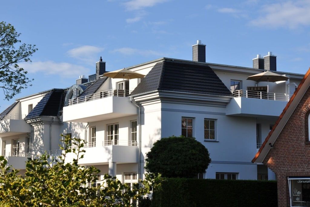 Un immeuble résidentiel à plusieurs étages, doté d’un style architectural moderne, avec des balcons et un toit plat.