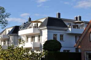 Un edifici residencial de diverses plantes amb un estil arquitectònic modern, amb balcons i teulada plana.