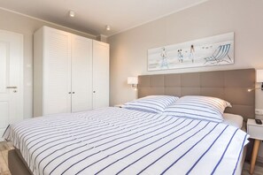 A bedroom with a large bed, a wardrobe, and a painting on the wall. - Holiday apartment with 1 bedroom (Zingst)