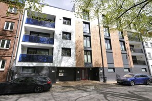 Ein mehrstöckiges Wohngebäude mit Balkonen, einer Garage und einer roter Tür.