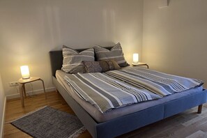 A bed with a blue headboard, two bedside lamps, and a striped blanket. - Holiday apartment with 1 bedroom (Schwerin)