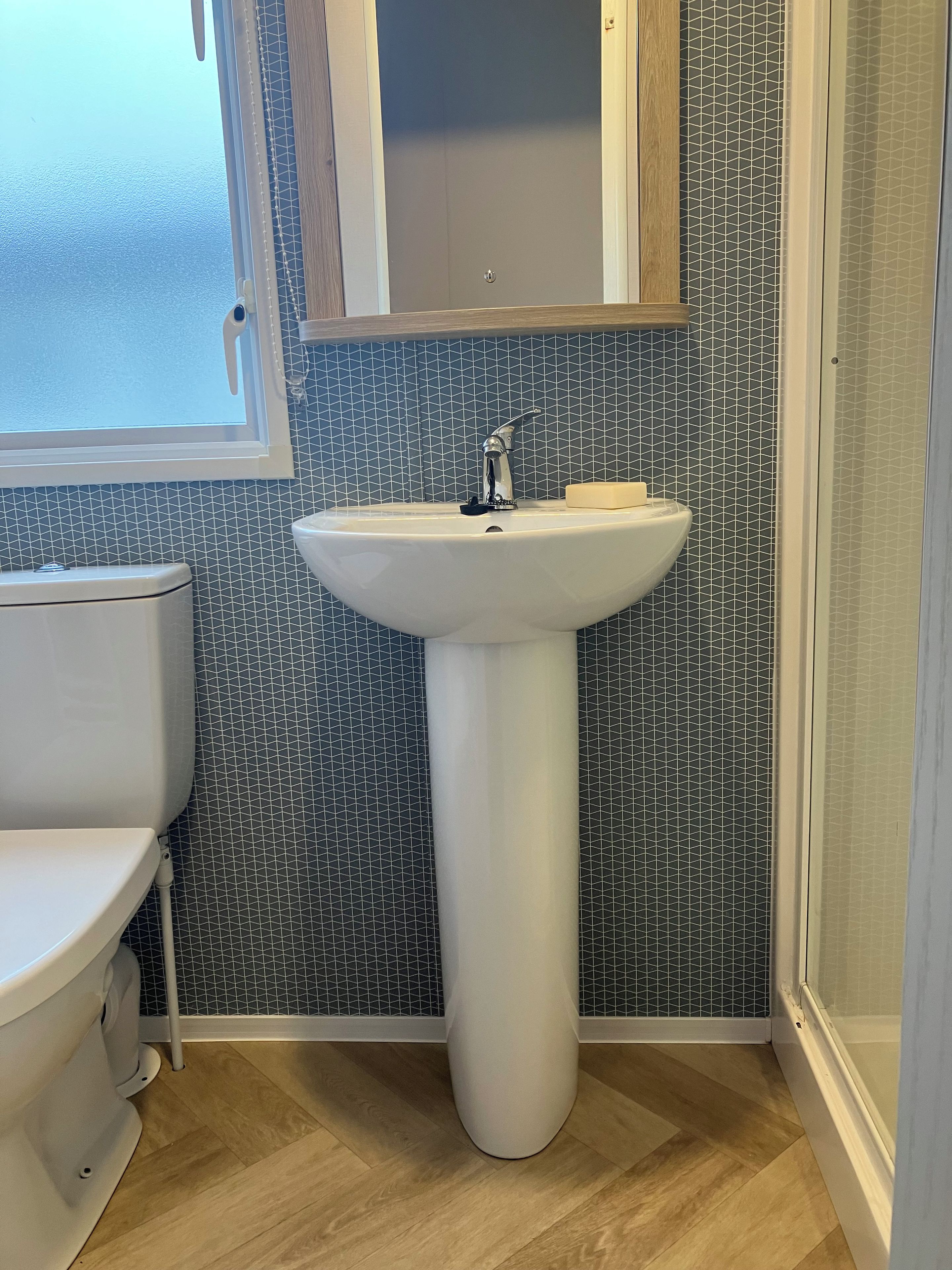Un baño con lavamanos pedestal blanco, inodoro y cabina de ducha.