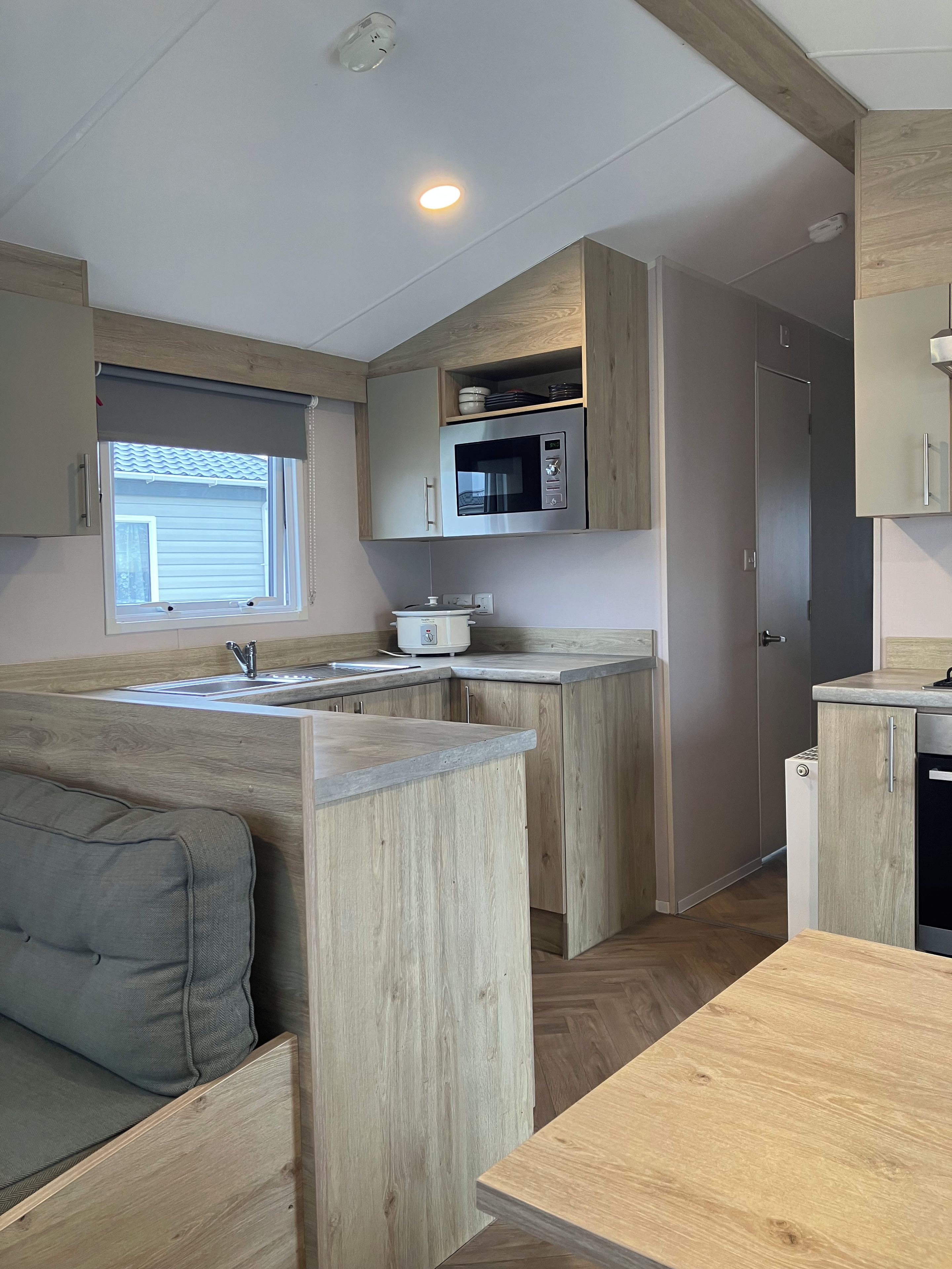 A compact kitchen with a built-in microwave, a sink, and wooden cabinetry.
