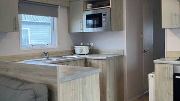A compact kitchen with a built-in microwave, a sink, and wooden cabinetry.