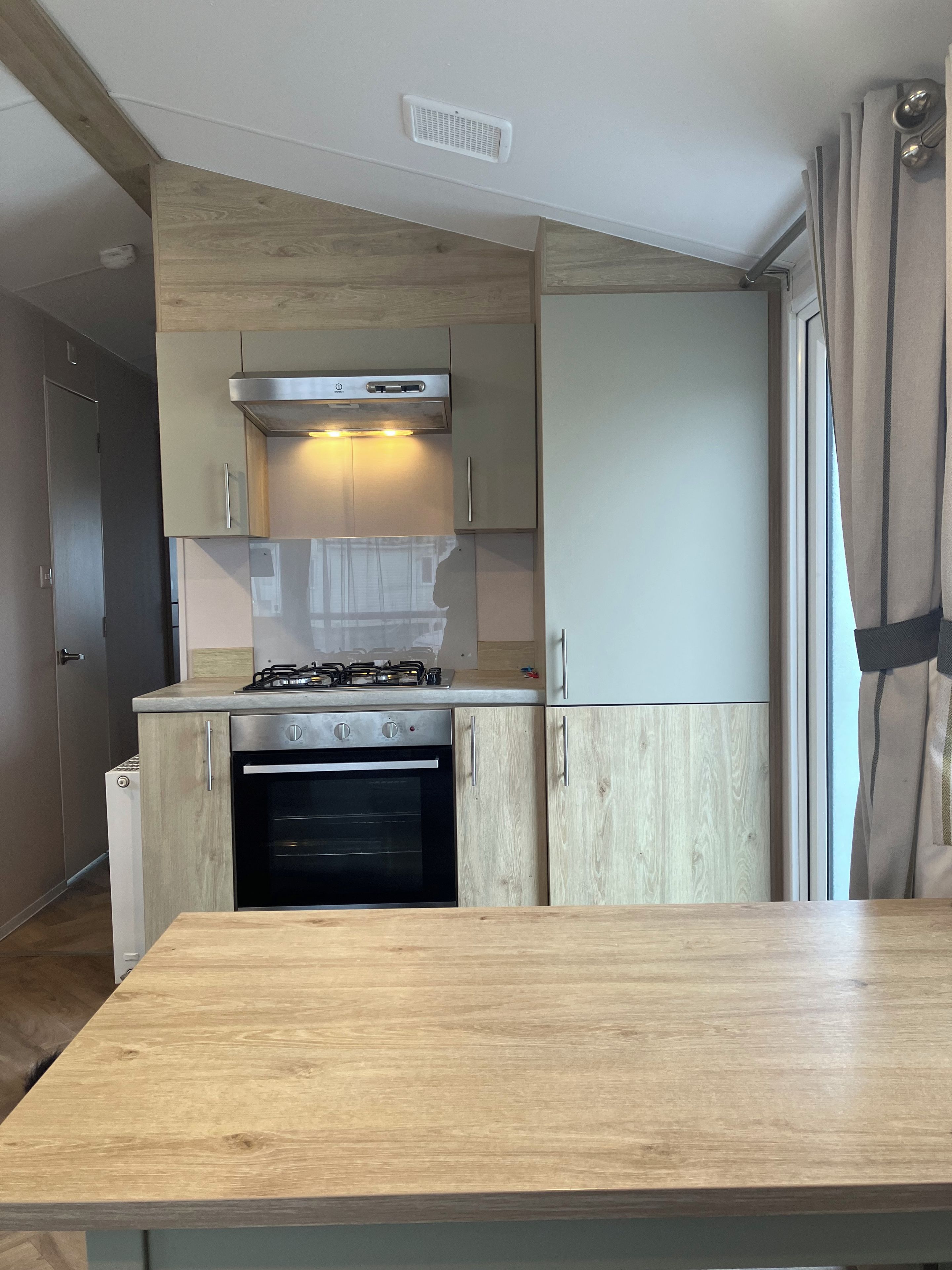 A modern kitchen with a gas stove, oven, and wooden cabinets.