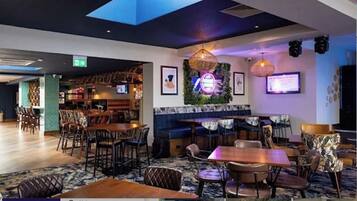 A modern restaurant with a variety of seating options including tables and booths, a bar area, and a stage for presentations.