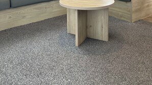 Un intérieur de camping-car moderne, avec un canapé modulable, une table ronde en bois et un coin cuisine.