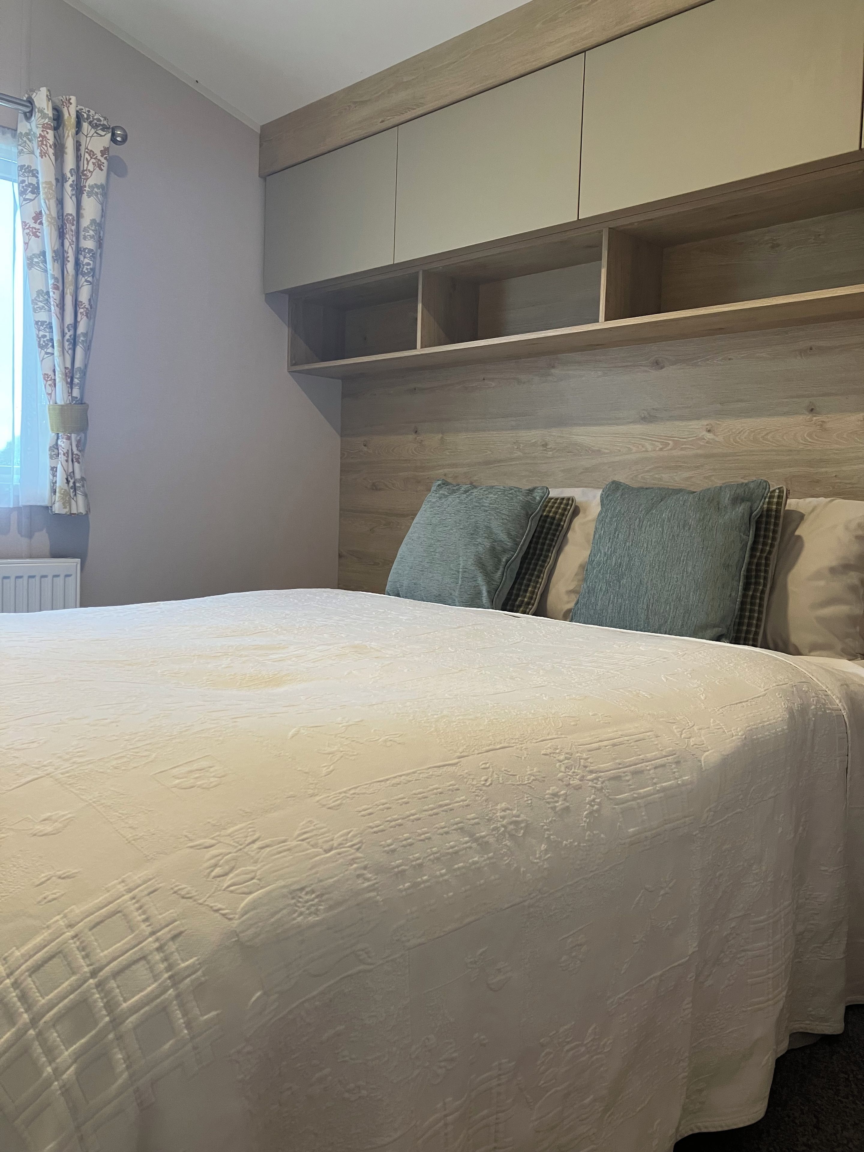A bedroom with a bed, a headboard, and a window with curtains.