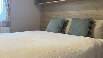 A bedroom with a bed, a headboard, and a window with curtains.