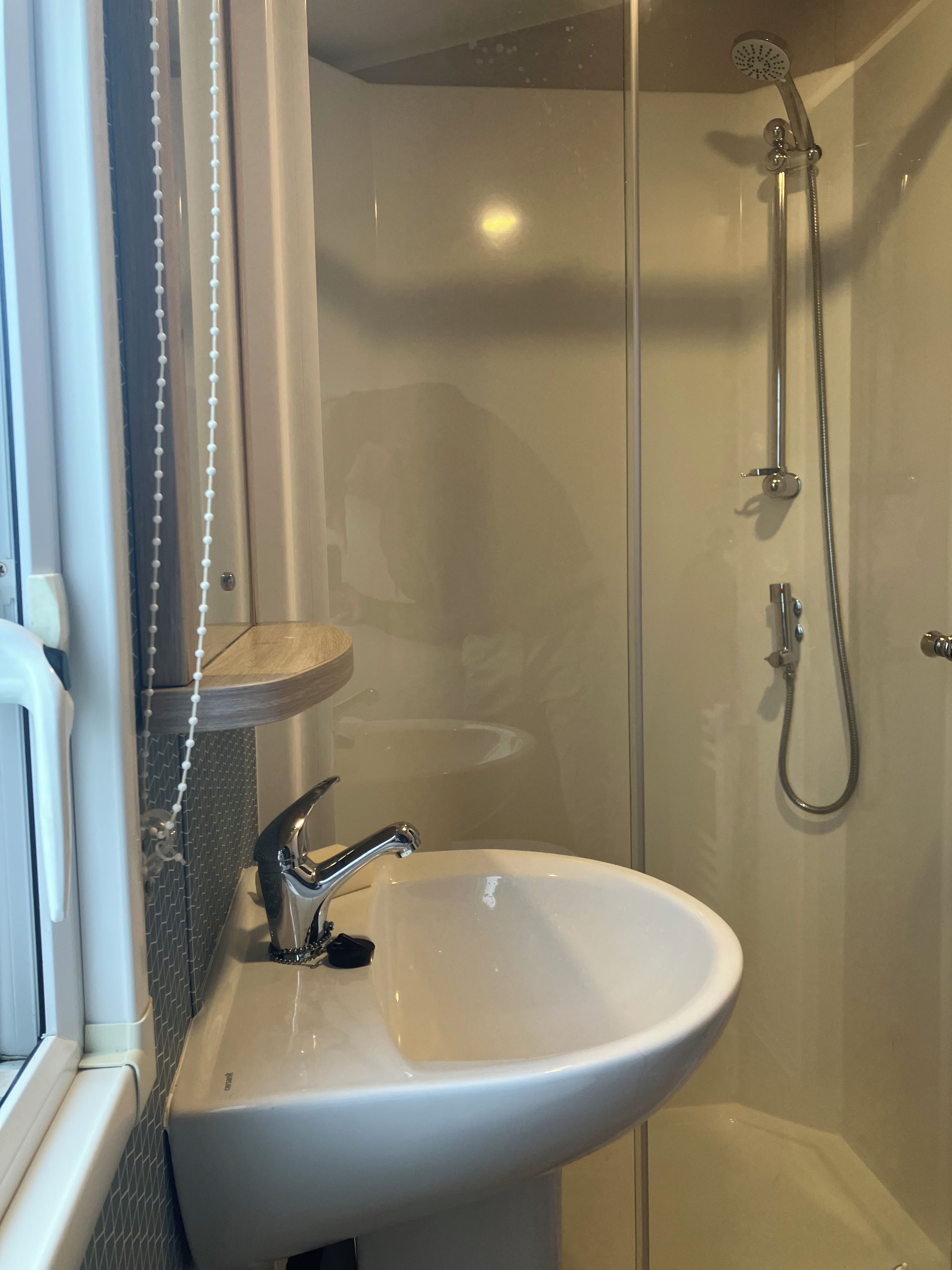 A bathroom with a white sink, a shower with a handheld showerhead, and a glass shower enclosure.