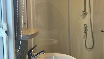 A bathroom with a white sink, a shower with a handheld showerhead, and a glass shower enclosure.