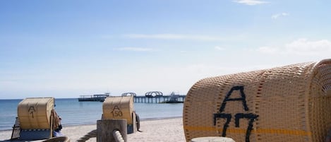 A beachside view with beach chairs and a wooden post with a rope.