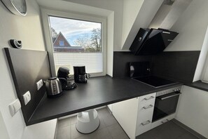 A compact kitchen with a window, a coffee maker, a kettle, a stove, and a microwave. - Seal U9 Neuharlingersiel (Neuharlingersiel)