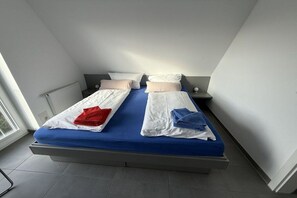 A twin bed with a blue mattress, white pillows, and a red towel on the left side. - Seal U9 Neuharlingersiel (Neuharlingersiel)