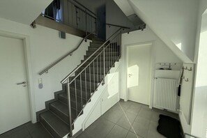 A staircase with metal railings leading to an upper floor, a white door, and a radiator on the floor. - Seal U9 Neuharlingersiel (Neuharlingersiel)