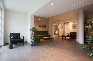 A spacious living area with a sofa, a chair, and a coffee table. There are potted plants and a staircase visible. - "EIGHT" at the Balmer See Residence (Benz-Balm)