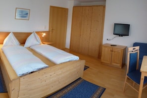 A bedroom with a wooden bed, a television, a wardrobe, and a chair. - 2 Apartment House Bauer (Mariapfarr)
