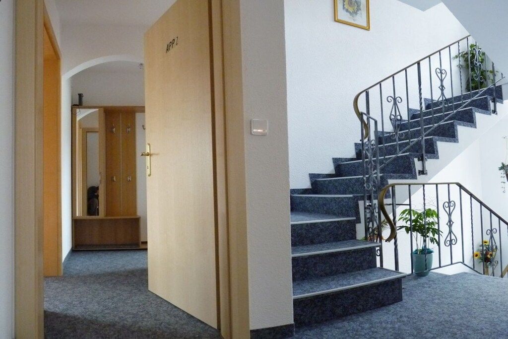 Una escalera con barandilla de metal y una planta en el rellano.