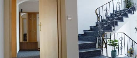 A staircase with a metal railing and a potted plant on the landing.