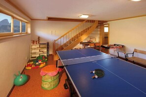 Una habitación con mesa de ping pong, una escalera y una ventana con vistas.