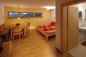 A room with a bed, a table, and a window overlooking mountains. - Holiday apartment with 1 bedroom (Damüls)