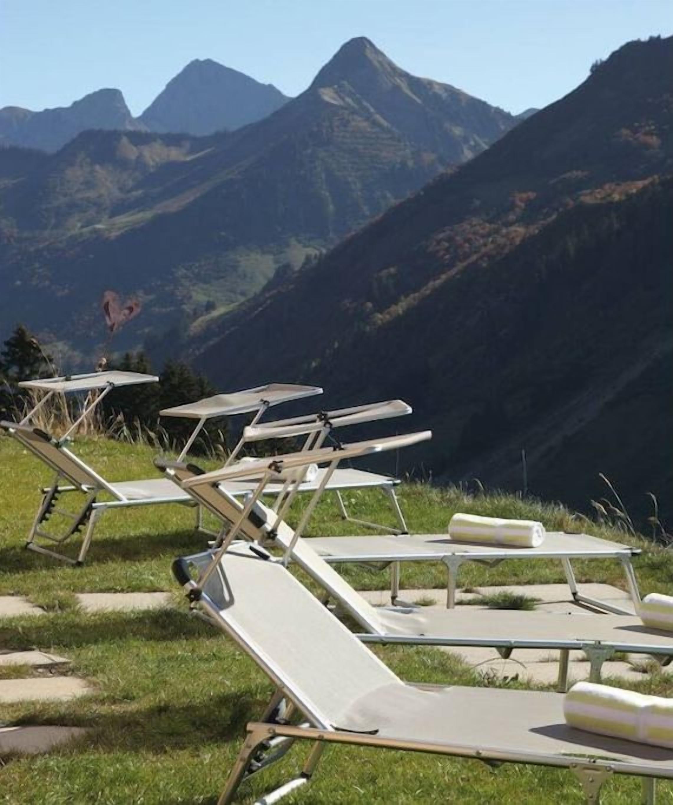 Loungestoelen staan op een gazon met een berg op de achtergrond.