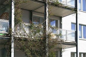Ein mehrstöckiges Gebäude mit Balkonen, auf einigen davon wachsen Pflanzen.