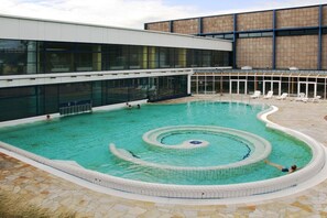 Ein Pool mit kreisförmigem Design, umgeben von Liegestühlen und einem Gebäude mit großen Fenstern.