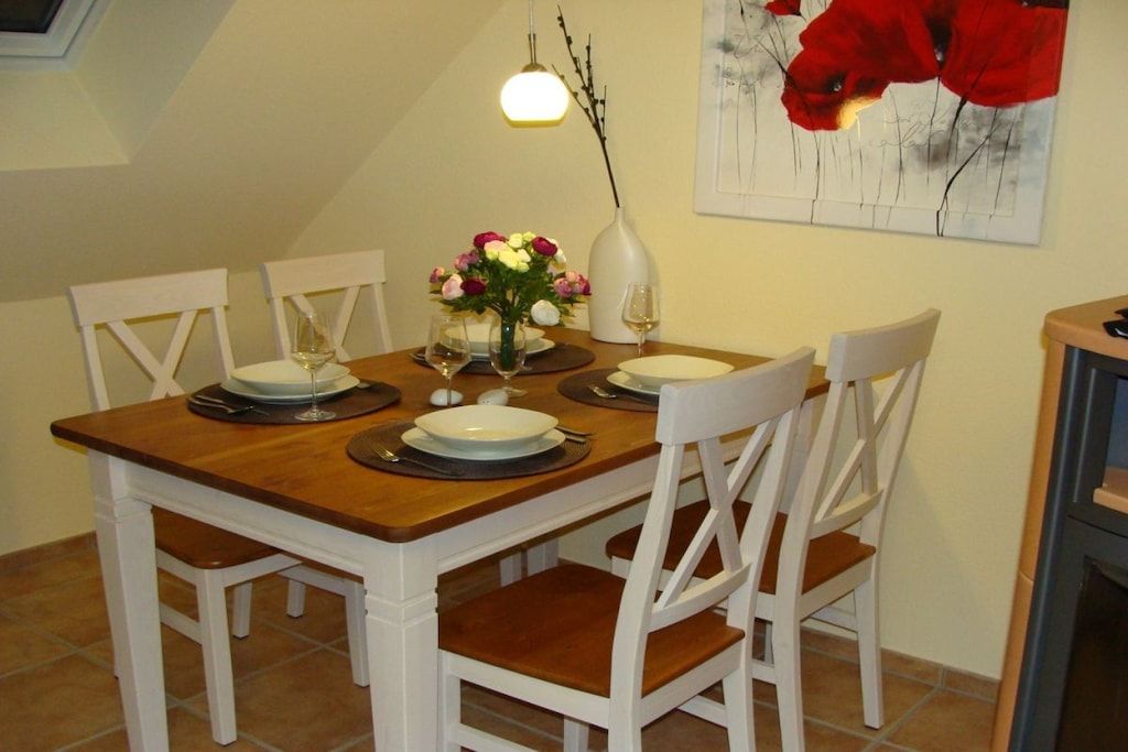 A dining table set with plates, glasses, and a vase of flowers.