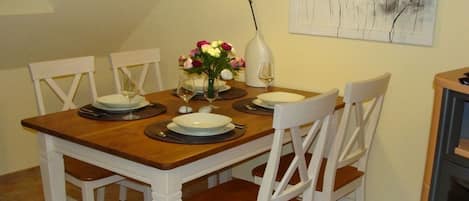 A dining table set with plates, glasses, and a vase of flowers.