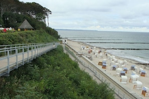A beach with a wooden walkway, beach chairs, and umbrellas. - Holiday apartment with 2 bedrooms (Ostseebad Nienhagen)