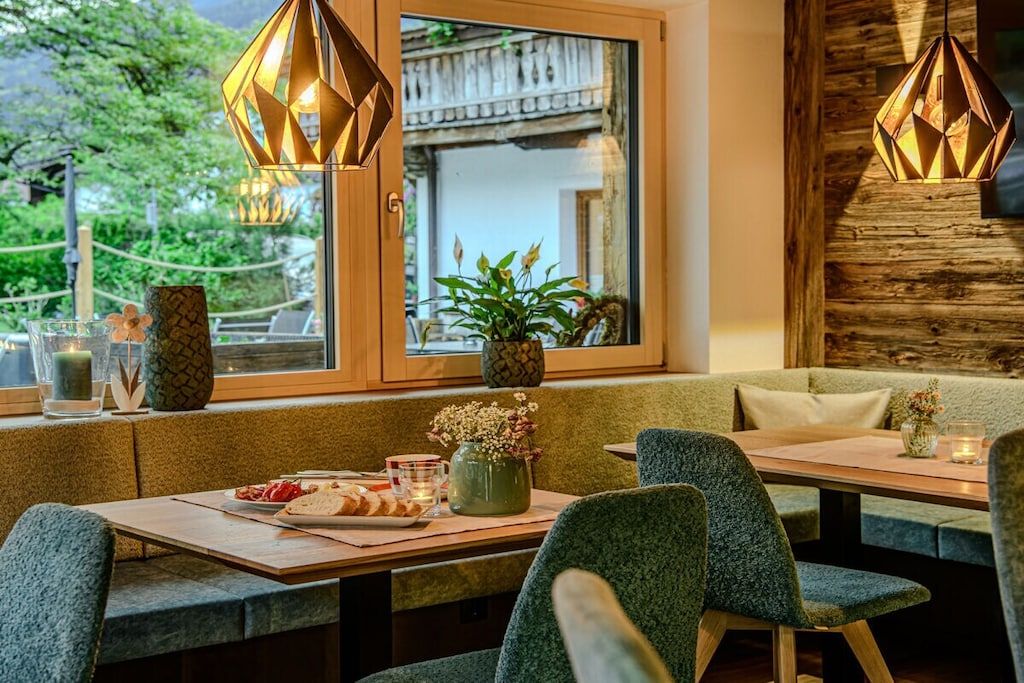 Un restaurant avec un décor intérieur en bois, une fenêtre offrant une belle vue et une table dressée avec de la nourriture et des boissons.