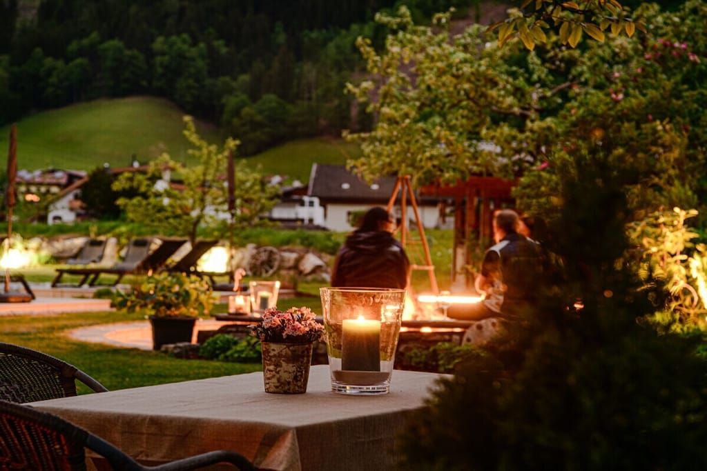 An outdoor dining area with a table set for two, a candle, and a potted plant.