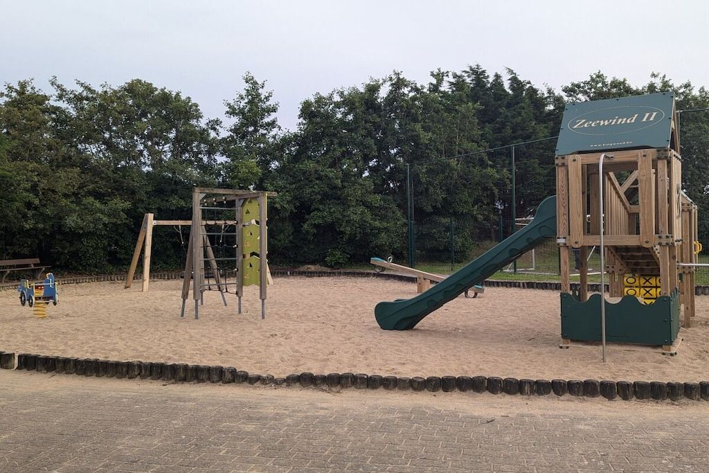 Un parque infantil con columpios, tobogán y estructura para escalar.