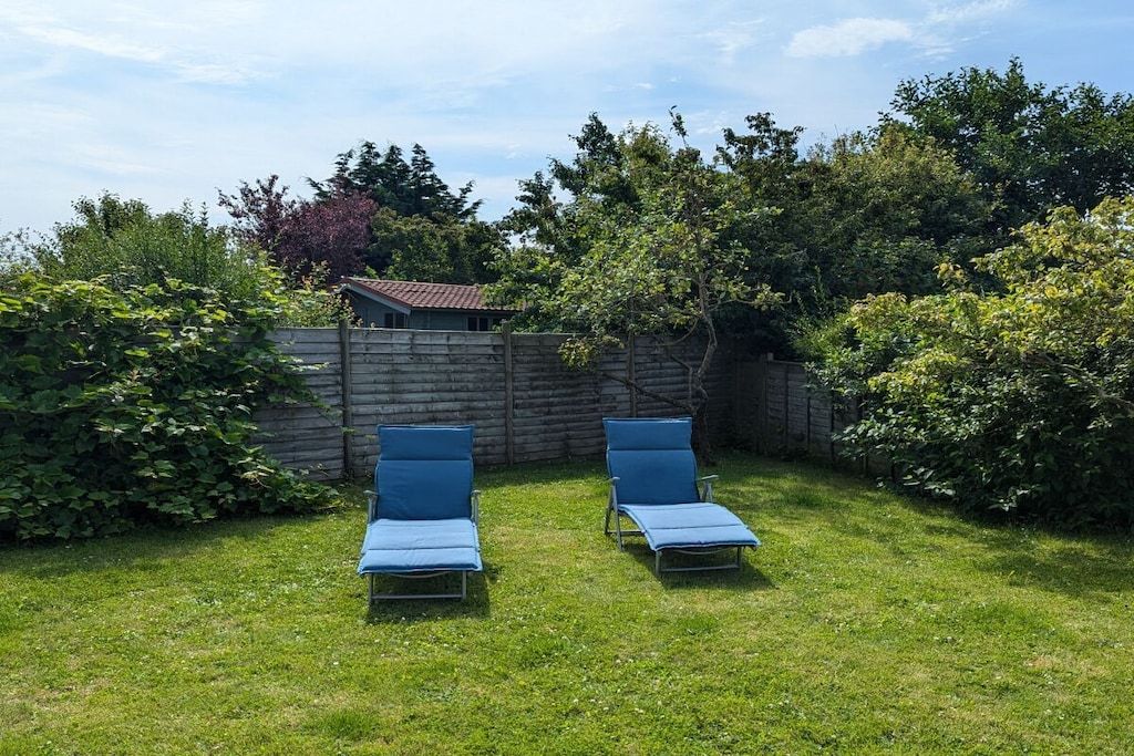 Un jardin avec deux chaises longues et une clôture en bois.