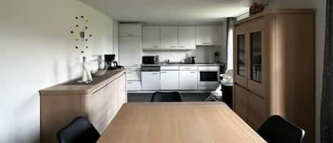 Una cocina moderna con armarios blancos, una mesa de comedor de madera y sillas negras.