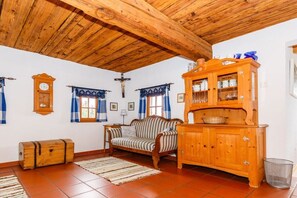 Ein gemütliches Zimmer mit Holzboden, einem Sofa, einem Schrank und einer Uhr an der Wand.