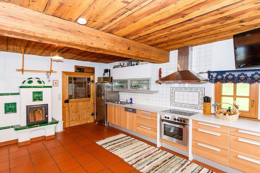 Een keuken met houten balken, een fornuis, oven en een koelkast.
