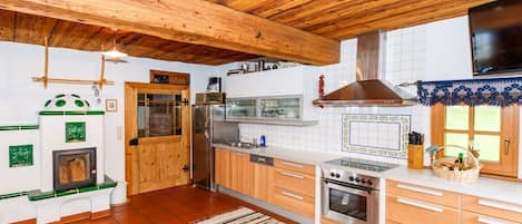 Une cuisine avec des poutres en bois, une cuisinière, un four et un réfrigérateur.