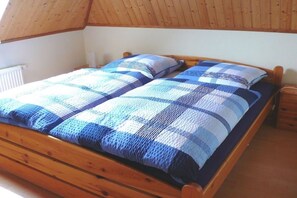Ein hölzernes Bett mit karierter Bettdecke und Kissen.