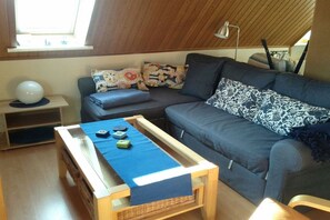 En hyggelig stue med en sofa, et lille bord med et blåt stof og en lampe.