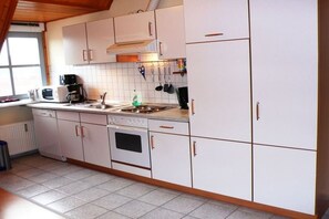 Et køkken med hvide skabe, en komfur, en mikrobølgeovn og et vindue.