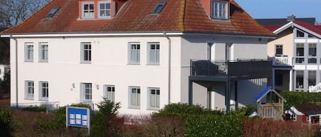 Un bâtiment à deux étages, avec un toit recouvert de tuiles rouges, de nombreuses fenêtres et un balcon.
