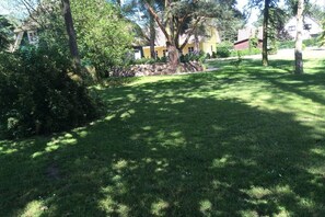 A well-maintained grassy area with trees and a building in the background. - Haus Wels in Born a. Darss (Born a. Darß)