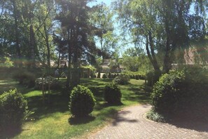 A paved garden path leading to a building, surrounded by well-maintained grass and trees. - Haus Wels in Born a. Darss (Born a. Darß)